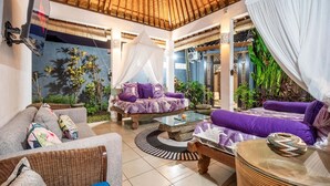 A cozy living area with a thatched roof, comfortable seating, and lush indoor plants. - Romantica Villa with Private Pool in Ubud (Ubud)