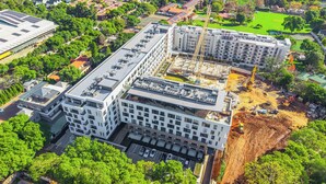 Ein mehrstöckiges Gebäude mit Dachterrasse, umgeben von Grünflächen und weiteren Gebäuden.