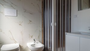 Une salle de bain équipée de toilettes, d’un bidet et d’une douche.