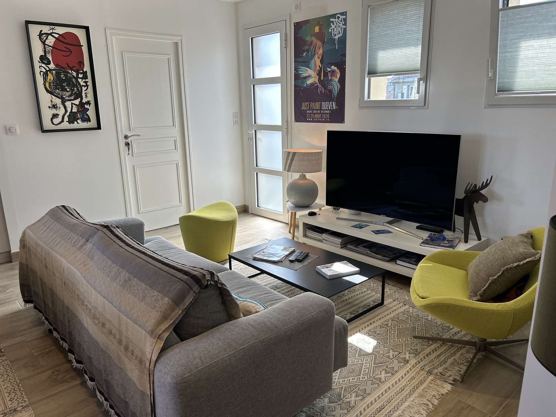 A living room with a sofa, yellow armchair, and a television.