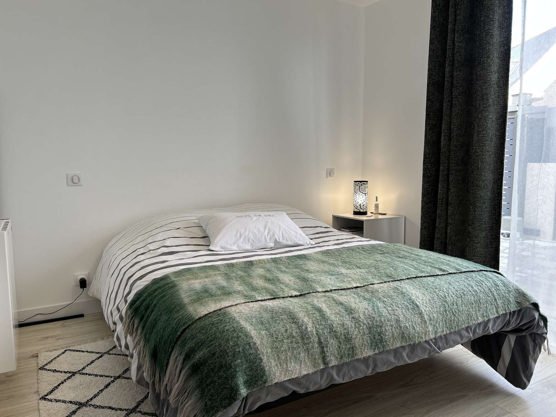 Una camera da letto ordinata con un letto, un comodino e un tavolino con una lampada.