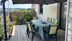 Une terrasse avec une table et des chaises, un parasol et une vue sur le paysage urbain.