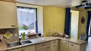 Eine Küche mit einer Arbeitsplatte aus Granit, einem Spülbecken und einem Fenster mit Blick auf ein Gebäude und Pflanzen.