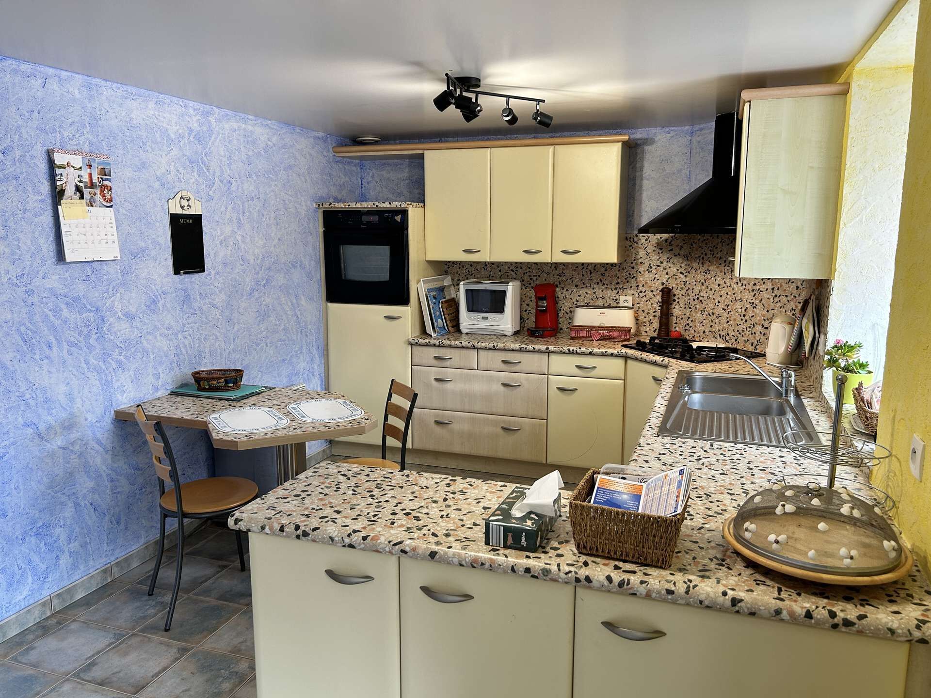 A compact kitchen with a small dining area, a microwave, a toaster, and a sink.