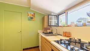 A kitchen with a green door, a window with a view, a sink, and a stove. - Family house in Pléneuf | 10 guests | Ref 1010 (PLENEUF VAL ANDRE)