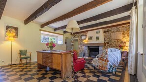A room with a checkered floor, a wooden desk with drawers, a red chair, a lamp, and a stone fireplace. - Family house in Pléneuf | 10 guests | Ref 1010 (PLENEUF VAL ANDRE)