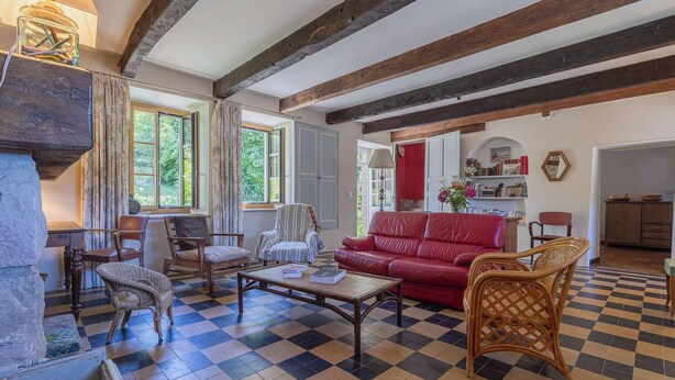 A room with a checkered floor, a red sofa, a wooden coffee table, and a wicker chair. - Family house in Pléneuf | 10 guests | Ref 1010 (PLENEUF VAL ANDRE)