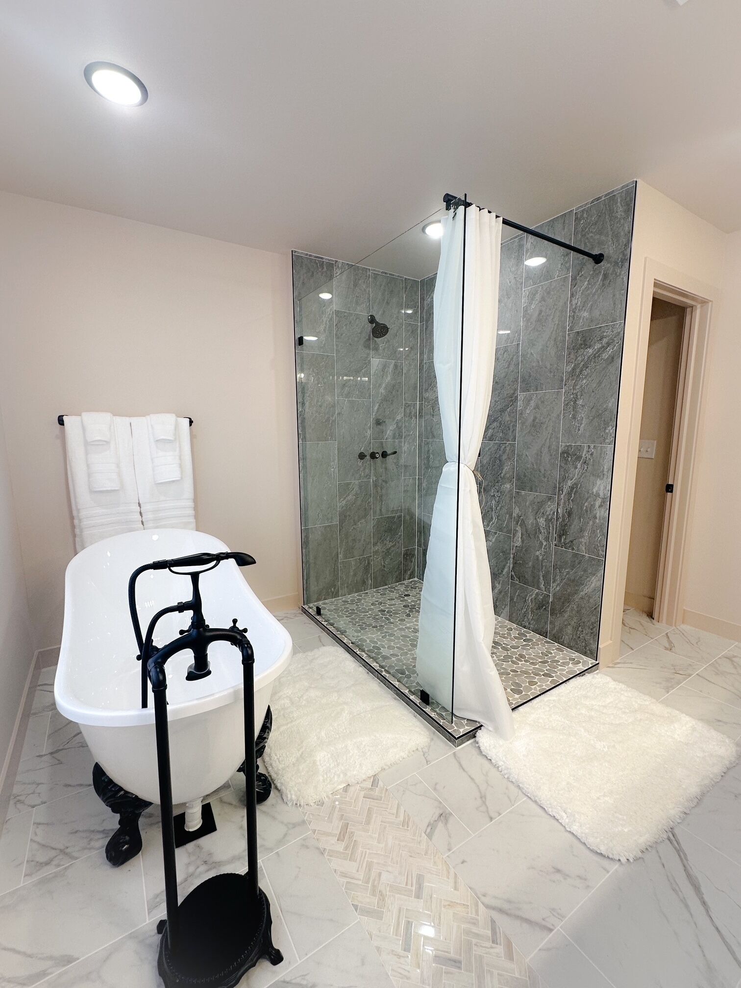 Une salle de bain avec une baignoire, un espace douche et un tapis blanc et moelleux.