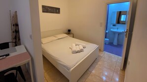 Ein Schlafzimmer mit Bett, Nachttisch und Schreibtisch mit Stuhl.