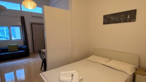 Ein modernes Hotelzimmer mit einem großen Bett, einem kleinen Nachttisch, einem Wandbild und Blick auf die Stadt durch das Fenster.