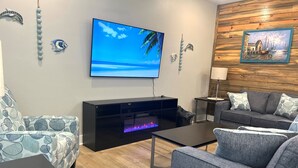 A modern living room with a flat-screen TV, a fireplace, and a wooden wall. - New Listing!  Oasis Bungalow (Rockport)