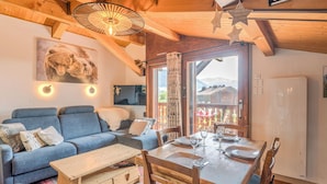 A cozy living room with a blue sofa, wooden dining table, and a ceiling fan.