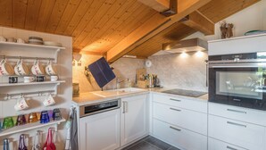 A modern kitchen with white cabinetry, a built-in oven, and a wooden ceiling.