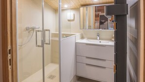 A modern bathroom with a glass shower enclosure, a white sink, and a mirror above the vanity.