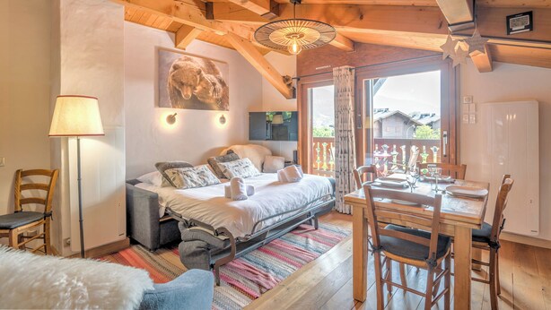 A cozy bedroom with a bed, bedside table, lamp, and a window with curtains.