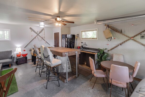 A compact kitchen with a wooden table, bar stools, and a ceiling fan.