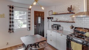 A kitchen with a wooden table and chairs, a stove, and a microwave.