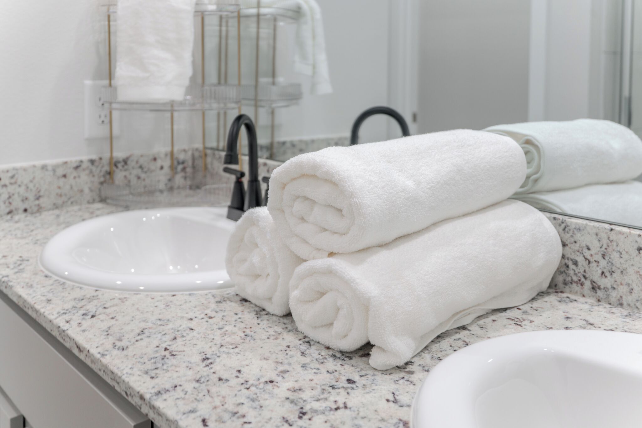 A bathroom with a granite countertop, a sink, and a towel rack with folded towels.