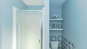 Une salle de bain avec une porte blanche, des toilettes et des étagères ornées d’objets décoratifs.