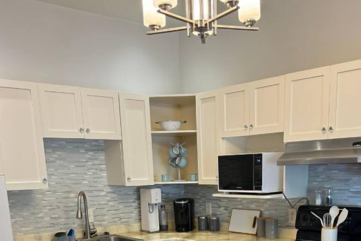 A modern kitchen with white cabinets, a stainless steel dishwasher, a microwave, and a stove.