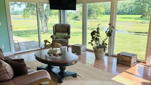 Un salon spacieux doté d’une grande fenêtre, d’un ventilateur de plafond, d’un canapé confortable, d’une table basse et d’un téléviseur.