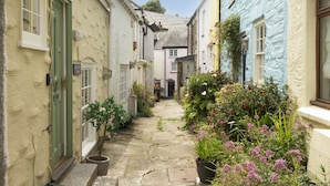 A narrow alleyway between buildings with a sign for 'Boseley Arms Cottage'.