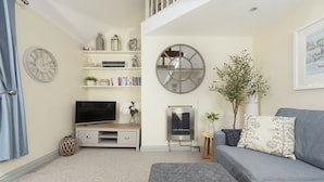A living room with a flat-screen TV, a fireplace, a sofa, and a bookshelf.
