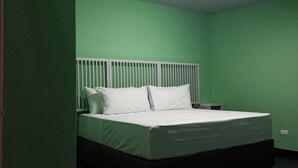 Une chambre avec un lit, une table de chevet et un luminaire au plafond.