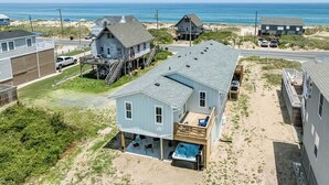 A two-story house with a large deck and a hot tub, located near a beach with a view of the ocean. - A Salty Pause | 50 ft to the beach | Hot Tub (Kitty Hawk)