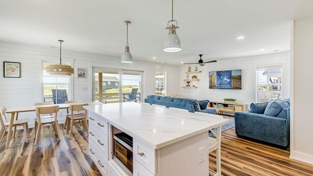 A spacious kitchen with a large island, wooden flooring, and pendant lighting. - A Salty Pause | 50 ft to the beach | Hot Tub (Kitty Hawk)