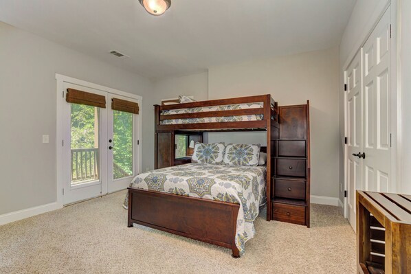 A bedroom with a bunk bed, a wooden dresser, and a door leading to a balcony. - Woodland Wonder - Starlit S'mores, Fireside Sips, Restful Vistas, Foosball, Lakes, Trails & Golf (Jasper)