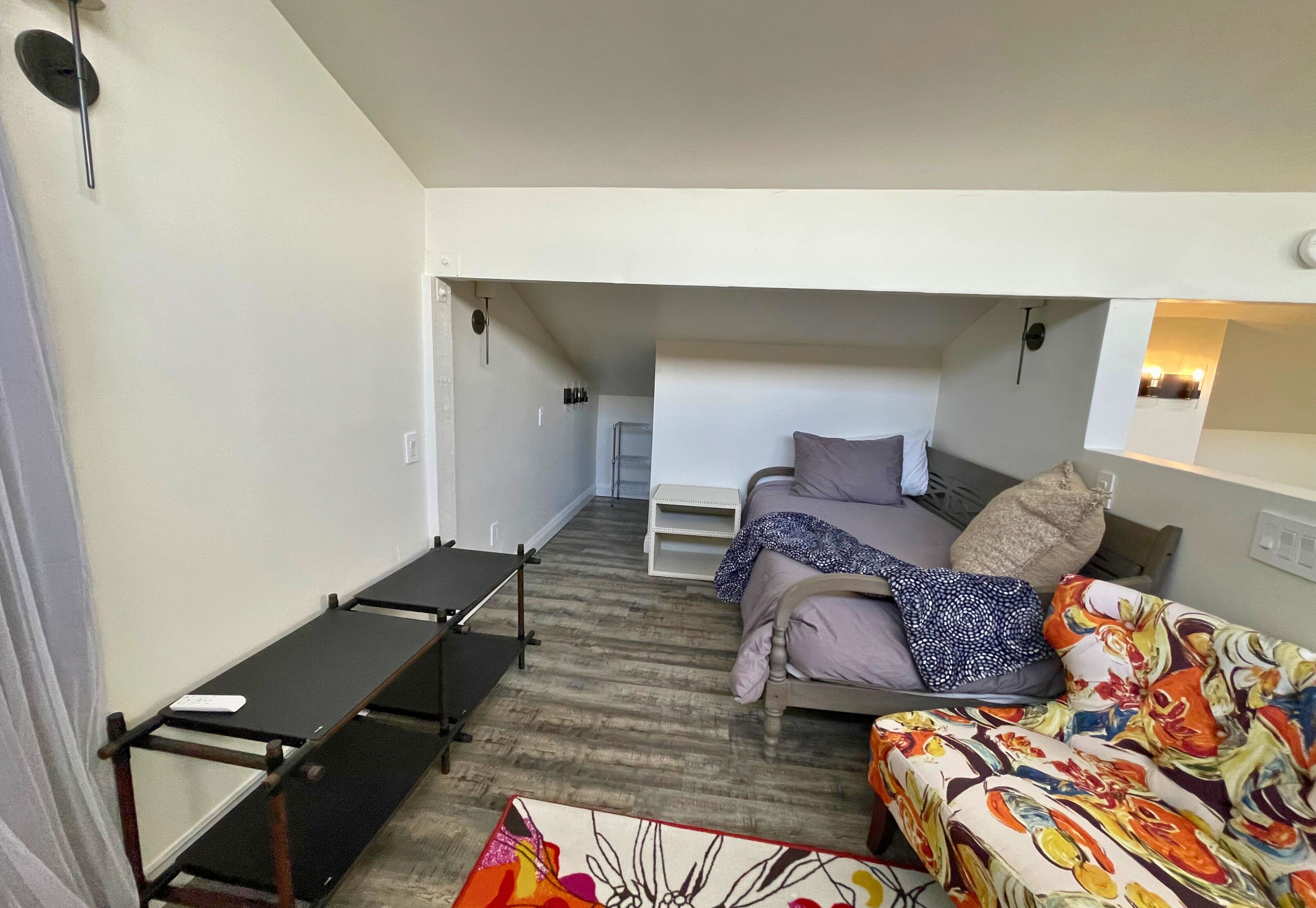 A compact room with a bunk bed, a sofa, and a small table.