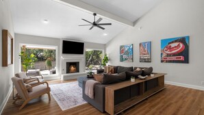 A modern living room with a fireplace, a large sofa, and a TV mounted on the wall.