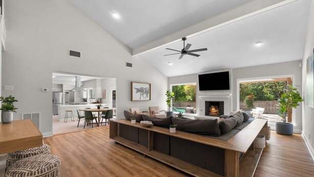 A spacious living area with a wooden bench, a fireplace, and a view of a backyard.