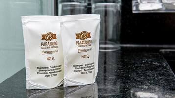 Dos bolsas blancas de champú del hotel Paradouro sobre una encimera.