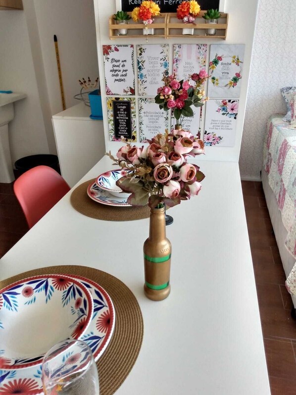 A dining table with a vase of flowers, plates, and a placemat. - Studio with balcony and wide view in Santana - SP, Jardim São Paulo subway, 12 min (São Paulo)