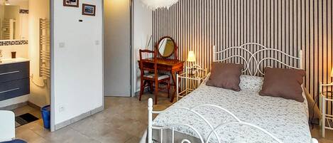 Ein Schlafzimmer mit Bett, Schreibtisch, Stuhl, Spiegel und einer gestreiften Wand.