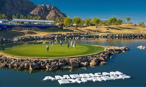 Un parcours de golf avec un étang et les mots « AMERICAN EXPRESS » inscrits sur la surface de l’eau.