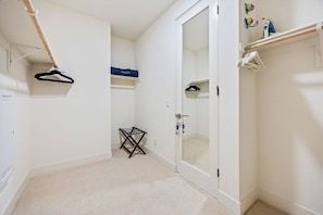Une pièce avec une porte blanche, un porte-manteau suspendu, une petite étagère sur laquelle se trouve un objet bleu, et un porte-serviettes blanc.