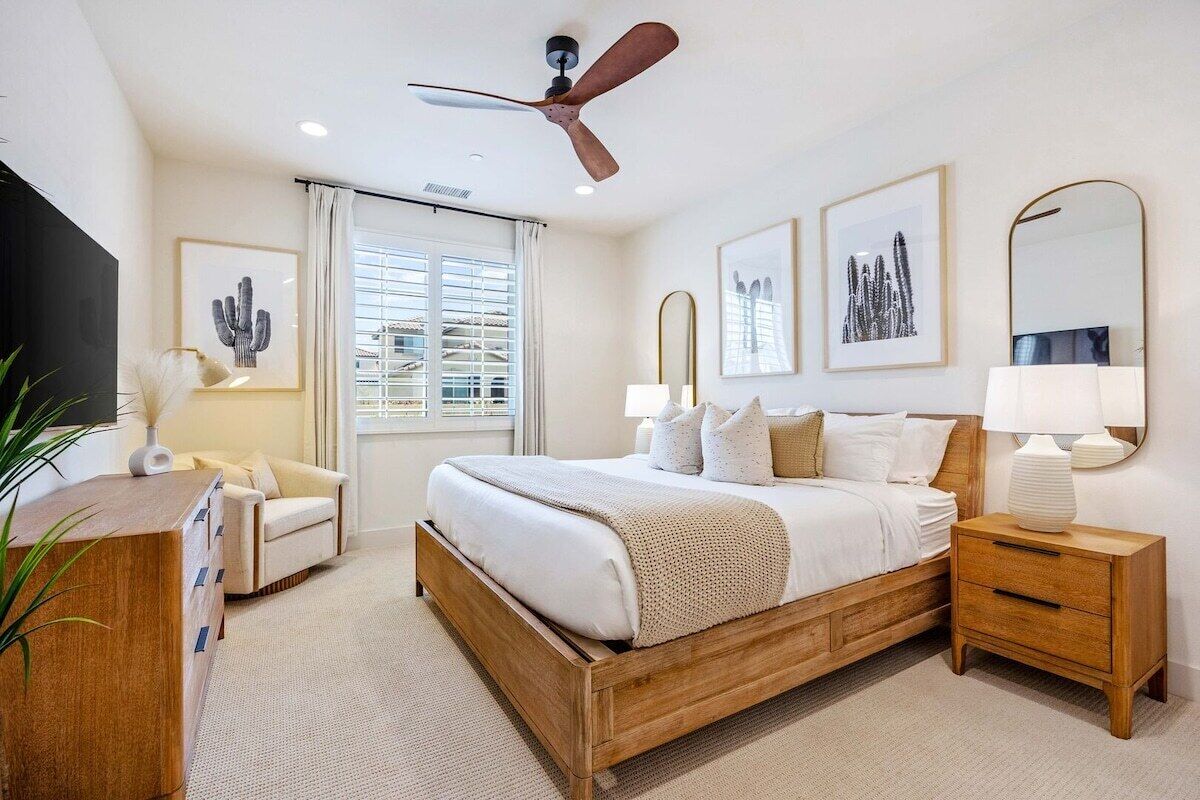 A bedroom with a wooden bed, bedside tables, a ceiling fan, and artwork on the walls.