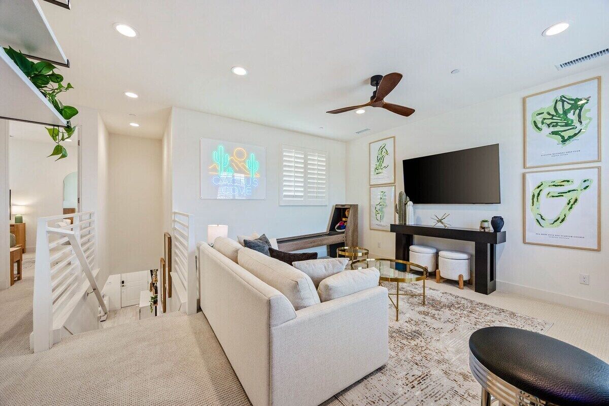 A modern living room with a sofa, a coffee table, and a flat-screen TV mounted on the wall.