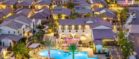 A residential area with multiple houses, a swimming pool, and a well-lit driveway.