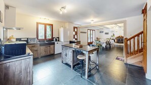 Une cuisine moderne dotée d’un îlot central, de meubles en bois et d’un coin repas agrémenté d’une cheminée.