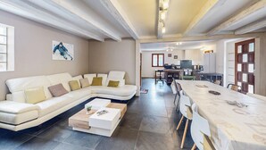 Un salon moderne comprenant un canapé d’angle, une table basse et un coin repas avec une table et des chaises.
