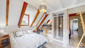 Une chambre à coucher comprenant un lit, une table de chevet, une fenêtre, un puits de lumière, un espace douche et une échelle en bois.