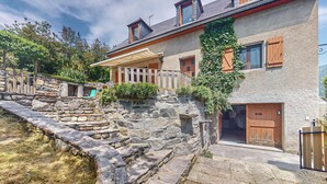 Un escalier en pierre menant à une porte en bois, un mur de pierre et un bâtiment avec des volets en bois et une clôture en bois.