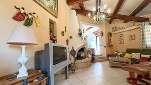 A cozy living room with a fireplace, a television, and a dining area with a lamp.