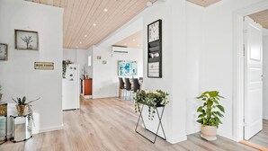 Un hall d’entrée spacieux avec un plancher en bois, un coin repas avec des chaises et une table, et un coin cuisine avec un réfrigérateur et un évier.