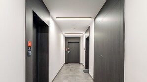 A modern, well-lit hallway with dark doors, a tiled floor, and a visible emergency exit sign. - 6th Floor Studio with the River View (Wrocław)