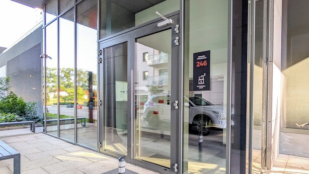 A modern building entrance with glass doors, a metal frame, and a sign indicating room number 246. - 6th Floor Studio with the River View (Wrocław)